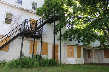 Old abandoned weathered boarded up historic country farmhouse with boarded up windows and peeling paint