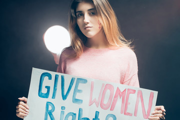 young caucasian feminist girl holding poster with inscription fight for women rights, calling for...