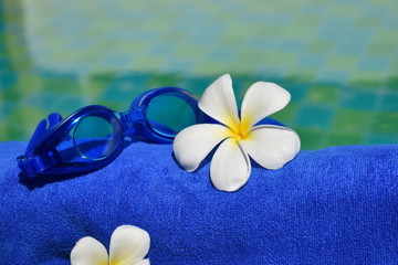 Fototapeta na wymiar Flowers, towel and water. Recreation at the pool. Tropical beauty spa. Relax and enjoy in the tropics.
