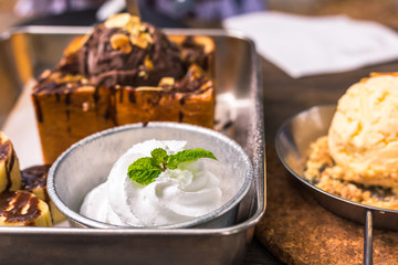 White ice cream in plate on the wood near Toast bread with chocolate ice cream.