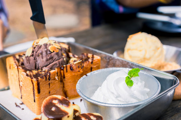 White ice cream in plate on the wood near Toast bread with chocolate ice cream.