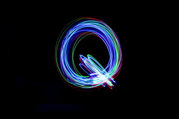 Long exposure photograph of a letter q in neon colour in an abstract swirl, parallel lines pattern...