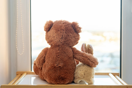 Naklejki Pair of toys. Bunny and teddy bear  Embracing loving teddy bear toy and bunny sitting on window-sill