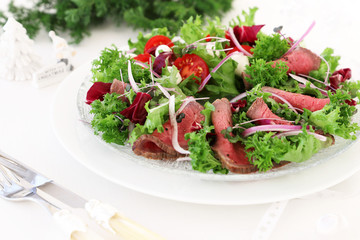 Holiday salad with roast beef on christmas decoration background
