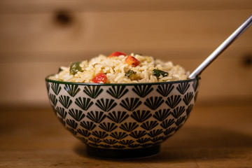 Appetizing healthy rice with vegetables in a bowl on a wooden background