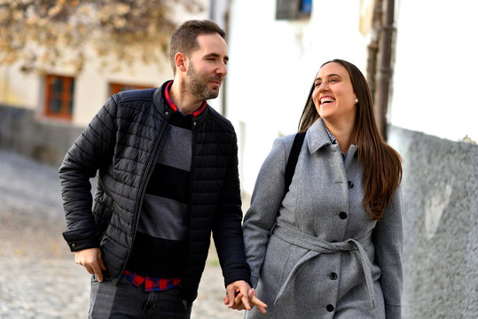 Beautiful Tourist Couple In Love Walking On Street Together. Happy Young Man And Smiling Woman Walking Around Old Town Streets, Looking At Architecture. Travel Concept. High Quality Image.