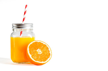 Glass jar with a tube with freshly squeezed orange juice stands on a white background next to fresh oranges