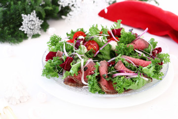 Holiday salad with roast beef on christmas decoration background