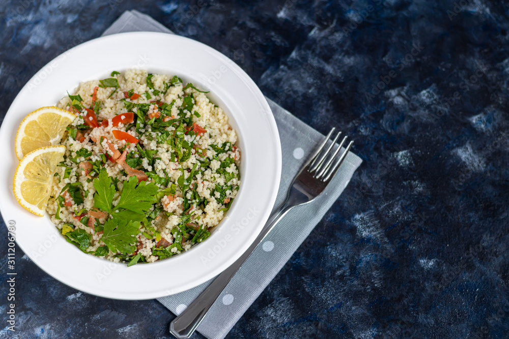 Wall mural tabbouleh salad in a round plate on a wooden background. salad in a white plate on a dark blue, tren