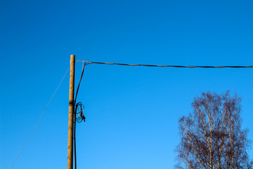 Electrtic wires and pole against blue sky