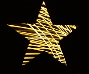 Long exposure photograph of gold fairy lights 'light painting' a star shape, vibrant color lights...