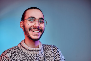 Joyful smiling man in winter sweater is posing for photographer at studio.