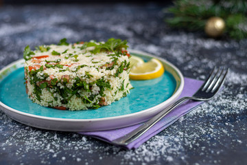 Tabbouleh  salad in a round plate on a wooden background. salad in a round plate on a dark blue, trendy background 2020.