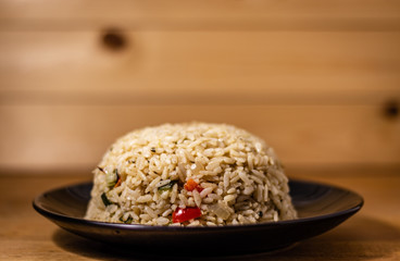 Appetizing healthy brown rice with vegetables on a wooden background