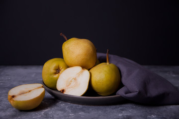 Ripe pears in a plate on dark background