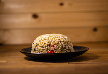 Appetizing healthy brown rice with vegetables on a wooden background
