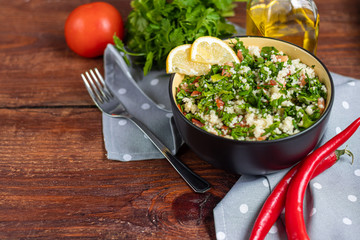 Tabbouleh  salad in a round plate on a wooden background.