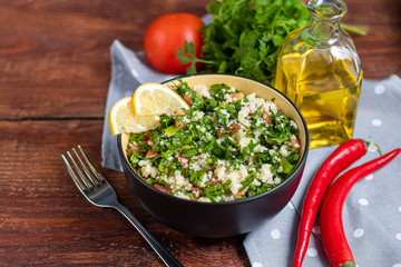 Tabbouleh  salad in a round plate on a wooden background.