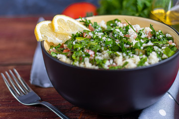 Tabbouleh  salad in a round plate on a wooden background.