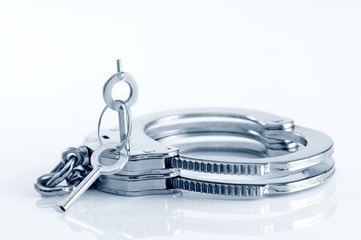 Close-up of metal handcuffs and key in keyhole