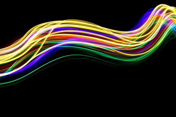 Long exposure photograph of neon multi colour in an abstract swirl, parallel lines pattern against a black background. Light painting photography.