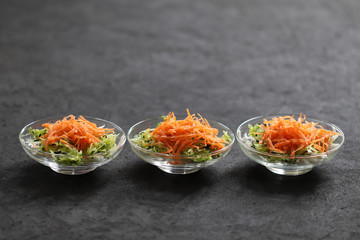Vegetable salad of carrots, cucumber and cabbage in a Cup on a dark background