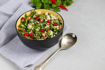 Tabule salad in a round plate on a light gray background under concrete.