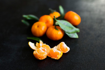  tangerines with leaves on a black background