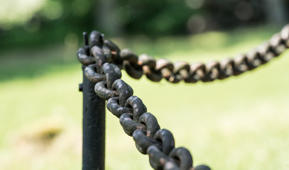 Old metal chain encircling protected area. Green natural bokeh background. Estonia, European Union.