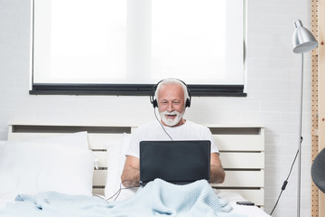 Senior man at home connected on laptop computer
