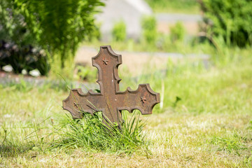 Old metallic rusted cross on graveyard, pentagrams on all three points. Green lawn surrounding the...