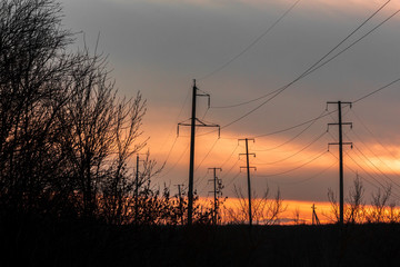high voltage power lines against a sunset in the field