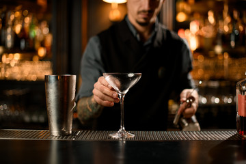 Bartender grabbing a cocktail glass for martini