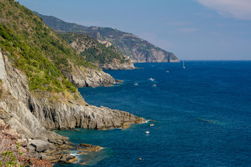 Fototapeta na wymiar Rocky coast near Riomaggiore with part of the Love Road (Via dell'Amore) in Cinque Terre National Park, Italy