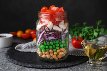 Healthy salad in glass jar on grey table
