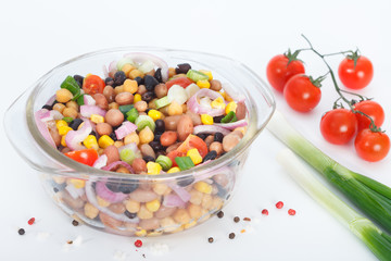 Vegetarian salad with mixed vegetables in glass bowl. Healthy vegan food with beans, cheakpeas, corn, tomato and onion.