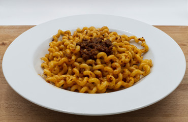 Fusilli Lunghi Bucati with bolognese sauce on a white plate, wooden table. Traditional italian pasta. 