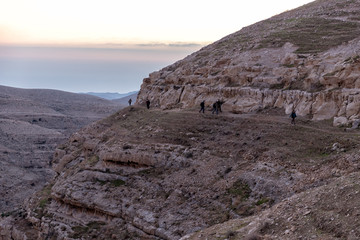 mountains in mar saba at sunrise with tourists hiking