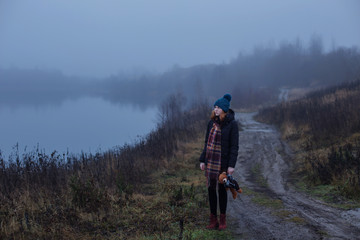 Sad teenager girl with  teddy bear on country road by foggy  lake.  Concept of adolescence and adolescent problems.