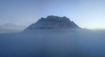 Zugspitze above the clouds and fog, mountain peak covered by snow, seen from Austria, Alps