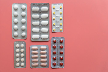 different blisters with tablets on pink background