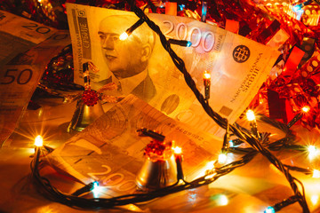 Close up shot of  Serbian 2000 paper money surrounded with Christmas decoration. Serbian money, Christmas bell and colorful lights.