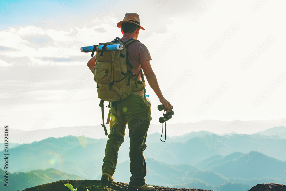 Wall mural the hiker with a backpack stood on the rock after examining the map to find a path in a beautiful mo