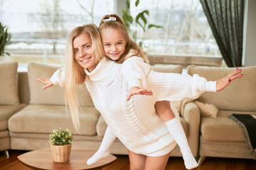 Joy, happiness and leisure time concept. Pretty girl with long hair having ride on her mother’s...