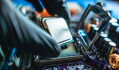 Engineer repairman holding hands CPU to insert into the socket of the motherboard. Technology hardware in the neon light
