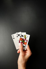 Cards in a hand on a black background. Three Card Poker. Rules and combinations of the game. Flush