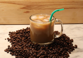 a cup of iced coffee with a straw, ice cubes and coffee beans for a base