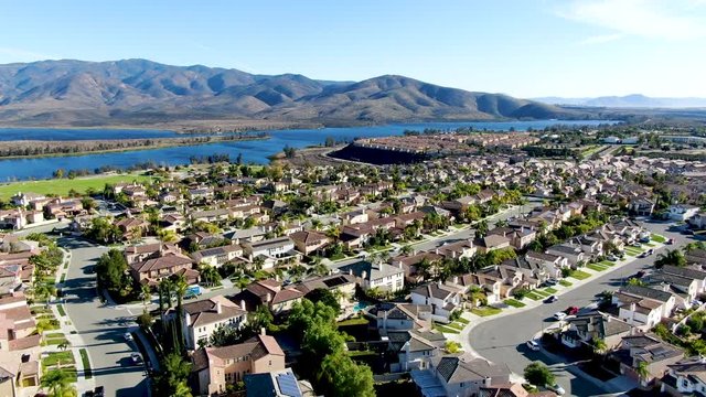 Aerial view of identical residential subdivision house with big lake and mountain on the background during sunny day in Chula Vista, California, USA.