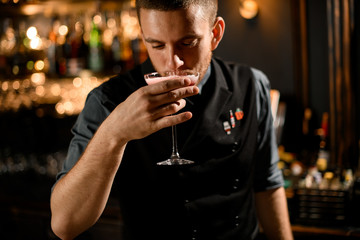 Bartender tasting a red delicious alcoholic cocktail drink with the white scum