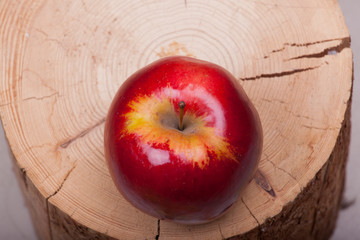 a large red apple photographed on a wooden stump